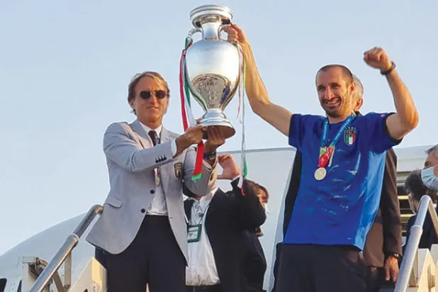 المدرب مانشيني (يسار) يشارك كيليني رفع كأس أوروبا لدى الوصول إلى مطار روما (أ.ف.ب)