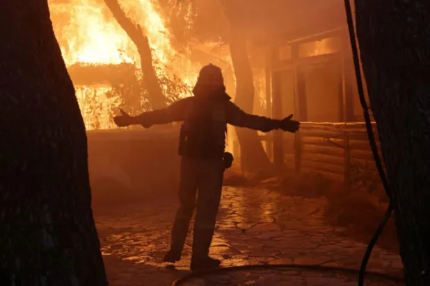 رجل إطفاء يعمل على إخماد حريق في شمال أثينا (رويترز)