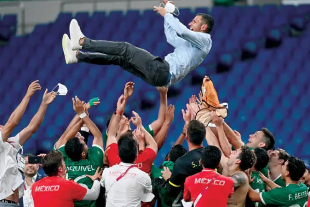 لاعبو المنتخب المكسيكي ومدربهم خايمي لوزانو في الهواء احتفالاً ببرونزية القدم الأولمبية (أ.ف.ب)