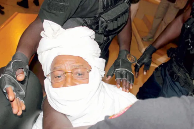 حسين حبري محاطاً بعناصر الأمن خلال محاكمته في دكار في يوليو (تموز) 2015 (أ.ب)