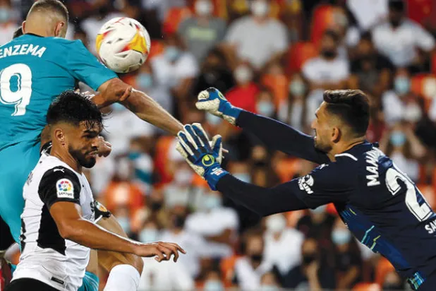 بنزيمة مهاجم الريال (يسار) يقفز عالياً مسجلاً برأسه هدف الفوز في مرمى فالنسيا (إ.ب.أ)