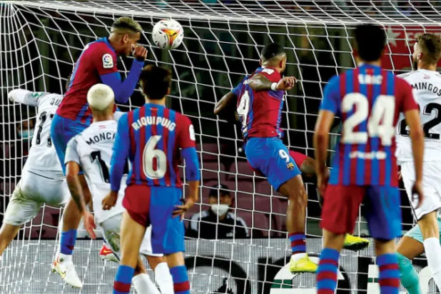 أراوخو (يسار) يقفز أعلى من الجميع ليسجل برأسه هدف إنقاذ برشلونة في مرمى غرناطة (إ.ب.أ)