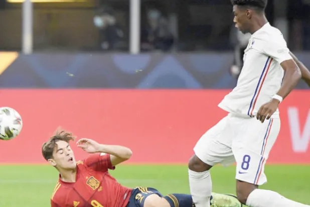 تشواميني (يمين) يستخلص الكرة من الإسباني جافي في نهائي دوري الأمم الأوروبية (رويترز)