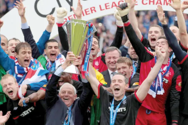 سميث يحمل كأس الدوري الاسكوتلندي محتفلاً مع فريق رينجرز الذي هيمن على البطولة معه (رويترز)