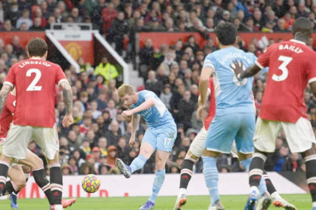 دي بروين نجم سيتي يسدد نحو مرمى يونايتد رغم حراسة المدافعين (أ.ف.ب)