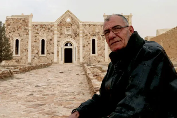 مطانيوس دلول من القلائل المتبقين في القريتين يقف أمام دير مار اليان  (أ.ف.ب)