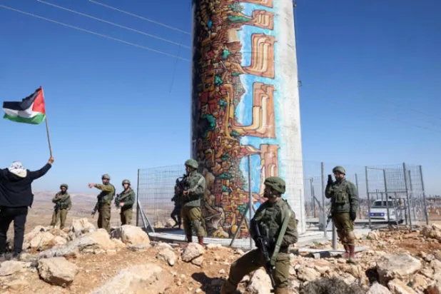 جنود إسرائيليون ينتشرون في مواجهة فلسطينيين يحتجون على مصادرة أرضهم لمصلحة مستوطنة «الكرمل» اليهودية قرب بلدة يطا جنوب مدينة الخليل بالضفة الغربية أمس (أ.ف.ب)