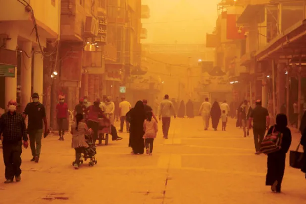 مواطنون في مدينة النجف أمس في ظل عاصفة ترابية جديدة تضرب العراق (أ.ف.ب)