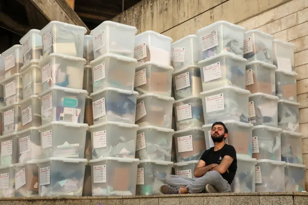 An electoral worker sits next to boxes as Lebanese await the official election results for the rest of the districts in Lebanon's parliamentary election, at the Justice Palace in Jdeideh, Lebanon May 16, 2022. (Reuters)