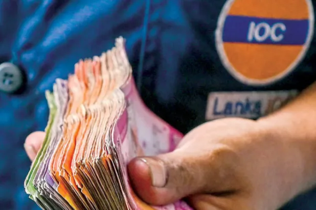 عامل في محطة وقود يحمل فئات نقدية من الروبية العملة المحلية لسيرلانكا (أ.ف.ب)