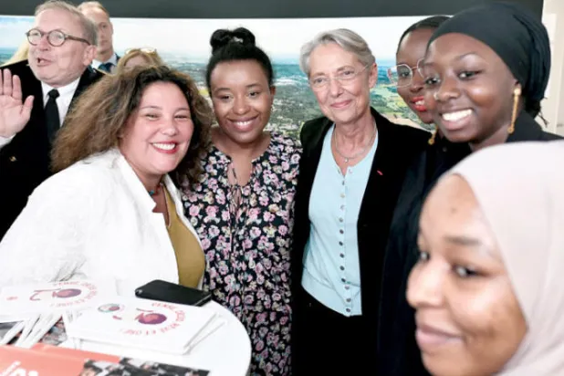 رئيسة وزراء فرنسا الجديدة إليزابيث بورن (وسط - الرابعة من اليمين) خلال زيارتها لإحدى ضواحي باريس أمس (أ.ف.ب)