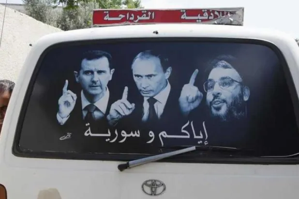 Lazkiye’de bir minibüste asılı olan, Esed, Nasrallah ve Putin’in bir arada göründüğü bir poster. (Reuters)