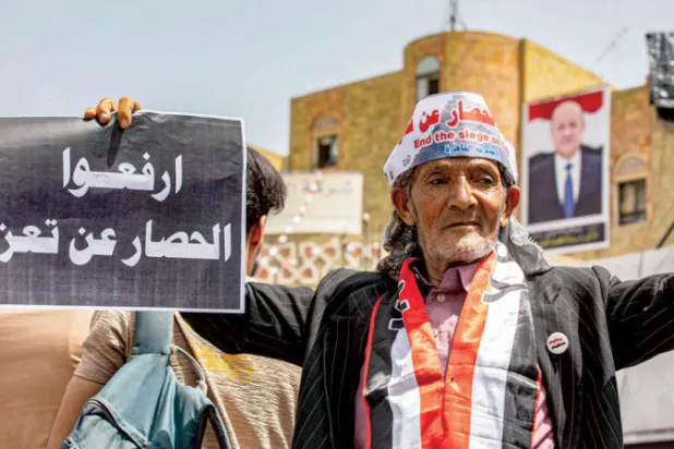 متظاهر يحمل لافتة ضمن حشود خرجت تنادي برفع حصار تعز أمس (أ.ف.ب)