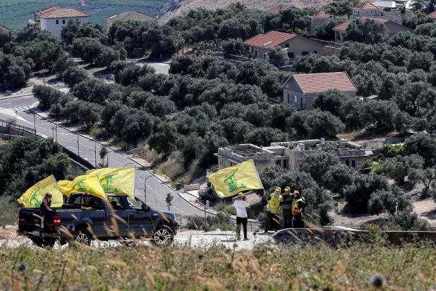 Hezbollah supporters pose for a photo with its flags in Sahl al-Khiyam (Khiyam plain) in southern Lebanon on May 25, 2022, near the northern Israeli town of Metula across the border (Background). (AFP)