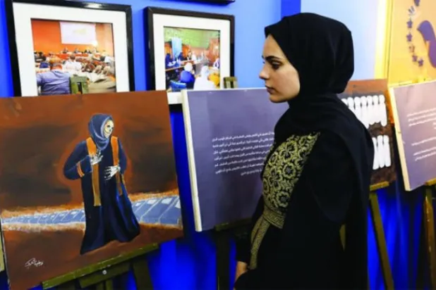 آرٹسٹ زینب القولق غزہ میں اپنی پینٹنگز دکھاتے ہوئے (رائٹرز)