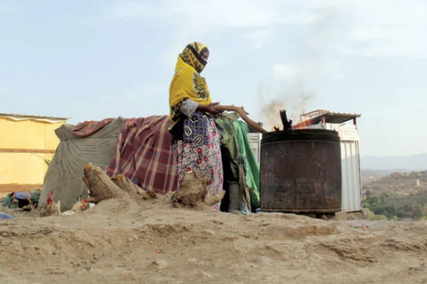 امرأة تحضّر طعاماً في مخيم نازحين في تعز (رويترز)