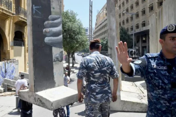 دو سیکورٹی اہلکار لبنانی پارلیمنٹ کے ہیڈ کوارٹر کی سڑکوں پر سیمنٹ کی رکاوٹ ہٹاتے ہوئے دیکھے جا سکتے ہیں (ای پی اے)