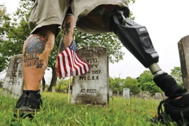 2008'de Irak'ta görev yaptığı sırada el yapımı patlayıcının infilak etmesi sonucu sağ bacağını kaybeden Christopher Gomez, Anma Günü kutlamalarına hazırlanırken Massachusetts'in New Bedford kentinde bir mezarlığa defnedilen askerlerin mezarlarına ABD bayrakları yerleştiriyor (The Standard Times / AP)