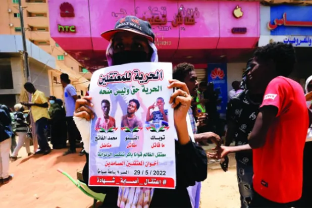 متظاهرة سودانية ترفع لافتة تطالب بالإفراج عن المعتقلين (رويترز)