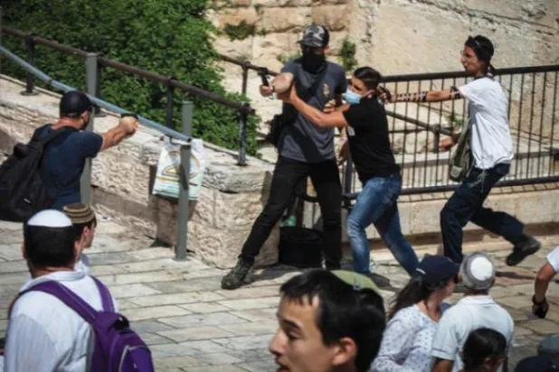 اتوار کو مشرقی بیت المقدس میں "فلیگ مارچ" کے دوران ایک اسرائیلی آباد کار کو فلسطینی صحافی پر بندوق تانتے ہوئے دیکھا جا سکتا ہے (ڈی پی اے)