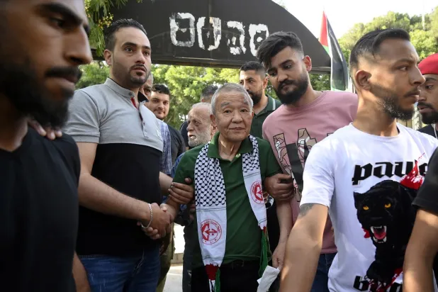 Kozo Okamoto (C), a former Japanese Red Army group member, arrives to attend a ceremony organized by Palestinians living in Lebanon to mark the 50th anniversary of the Lod airport attack, at the cemetery in the Shatila Palestinian refugee camp in Beirut, Lebanon, 30 May 2022. (EPA)