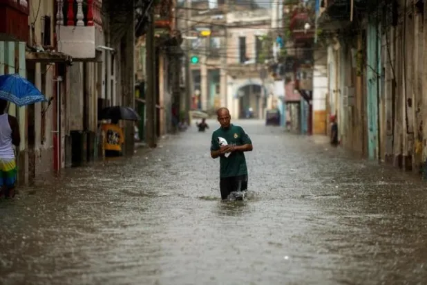 رجل يمشي وسط شارع غمرته المياه في كوبا (أ.ف.ب)