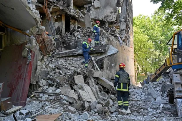 عمال الإنقاذ أمام أنقاض مبنى سكني مُدمر بسبب القصف الروسي على مدينة خاركيف الأوكرانية (أ.ف.ب)