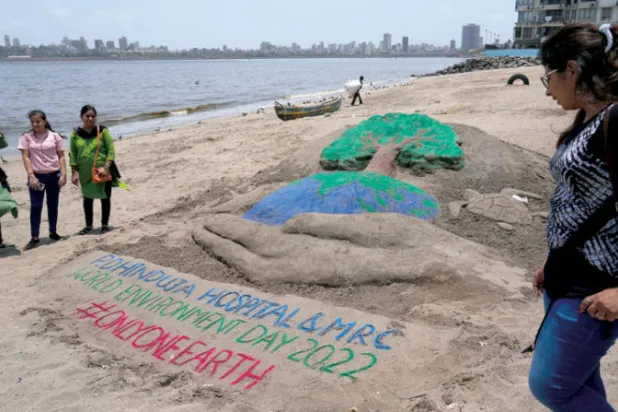 كتابات فنية على رمل أحد شواطئ مومباي في يوم البيئة العالمي (أ.ب)