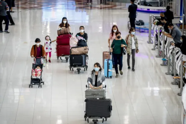 مسافرون يحملون أمتعتهم في مطار سوفارنابومي الدولي بتايلاند (إ.ب.أ)