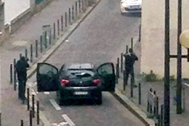 مسلحون يواجهون ضباط شرطة بالقرب من مكاتب صحيفة «شارلي إيبدو» الفرنسية في باريس 7 يناير 2015 خلال هجوم إرهابي خلّف 11 قتيلاً (أ.ف.ب)