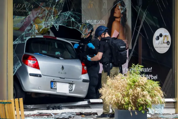 ضباط شرطة يقفون بجوار السيارة بعد اصطدامها بنافذة المتجر (رويترز)