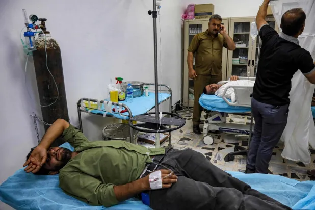 Injured men lie on hospital beds at a triage ward in a hospital as they receive care for their wounds following an overnight attack in Erbil, the capital of the Iraqi Kurdistan Region, on June 8, 2022. (AFP)