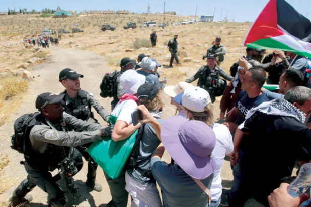 متظاهرون في مواجهة مع جنود الاحتلال في قرية يطا بالضفة الغربية أمس (إ.ب.أ)