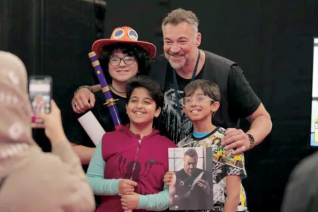 الممثل أليكس باونوفيتش يلتقط صورة مع بعض الأطفال الزائرين للمعرض (تصوير: عبد الله الفالح)