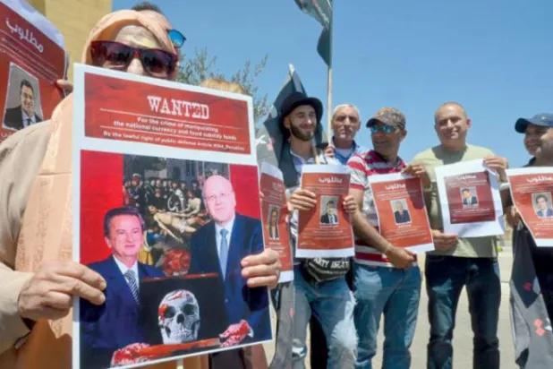 Göstericiler dün Beyrut şehir merkezindeki bir gösteri sırasında Lübnanlı banka sahiplerinin üzerinde "toplumun düşmanı" yazılı fotoğraflarını göstererek protesto düzenlediler (EPA)