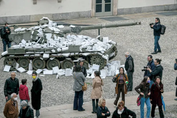 كتب تُرمى على دبابة كجزء من تركيب فني تفاعلي بعنوان «الثقافة فقط يمكنها إيقاف الحرب» في ساحة «ريال» بميلانو في 23 أبريل (أ.ف.ب)