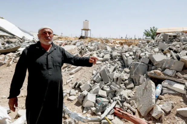 محمود نجاجرة يشير إلى منزله المهدم في مسافر يطا في الضفة الغربية نهاية مايو 2022 (رويترز)