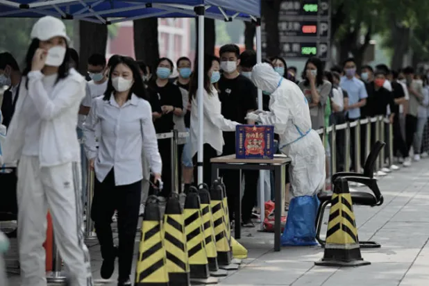 طابور طويل لسكان أحد الأحياء مصطفين لاختبار «كوفيد - 19» في بكين أمس (أ.ف.ب)