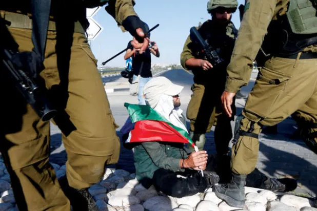 جنود يعتقلون نشطاء سلام حاولوا منع المستوطنين من نزع أعلام فلسطين في قرية عزون (إ.ب.أ)