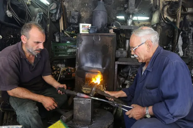 Syrian blacksmiths forge a cleaver in their workshop in the old city of the capital Damascus, on June 6, 2022. (AFP) 