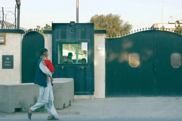 رجل يحمل طفلاً خارج السفارة البريطانية في العاصمة كابل (غيتي)