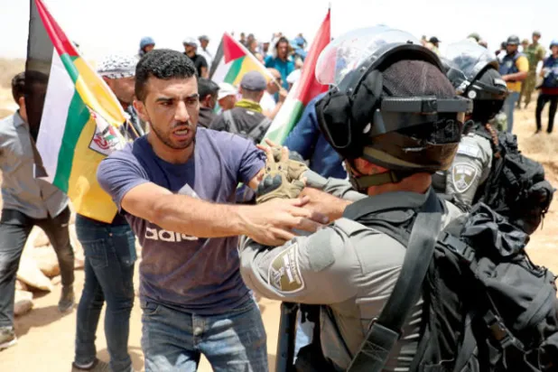 عراك بين فلسطيني وجندي إسرائيلي في بلدة يطا في الضفة الغربية أمس (إ.ب.أ)