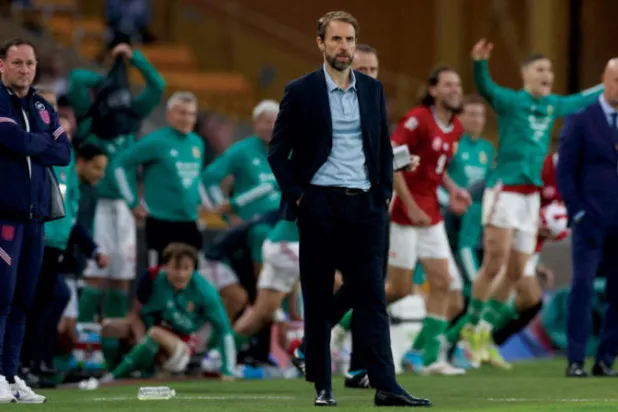 ساوثغيت مدرب إنجلترا يشعر بالحسرة بينما لاعبو المجر خلفه يحتفلون (رويترز)