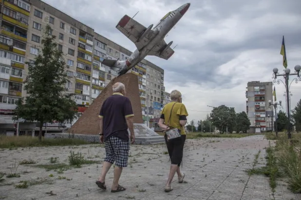 سكان يسيرون في أحد شوارع منطقة لوغانسك شرق أوكرانيا (إ.ب.أ)