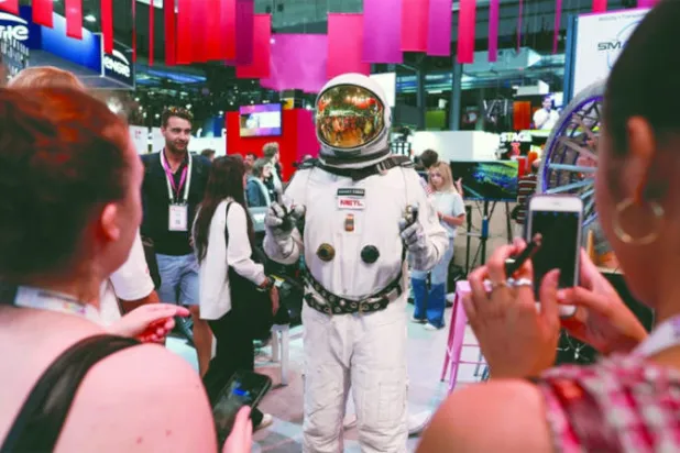 زائرة لمعرض «فيفا تكنولوجي» في فرنسا قبل أيام تلتقط صورة لرجل يرتدي بذة رائد فضاء (رويترز)