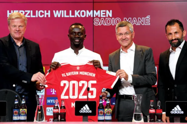 ماني يستعرض قميص البايرن بين رئيس النادي هربرت هاينر والرئيس التنفيذي أوليفر كان (رويترز)