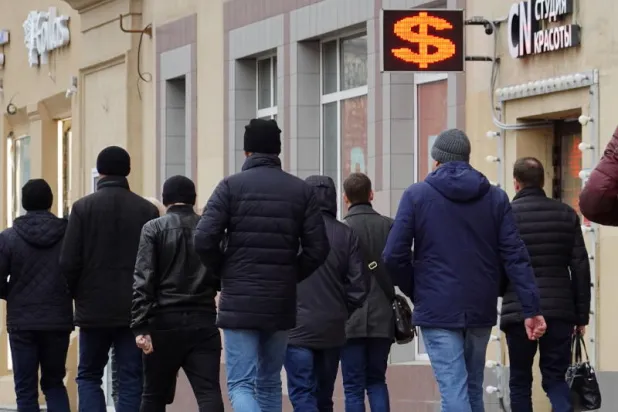 أشخاص يسيرون أمام مكتب صرافة في موسكو (إ.ب.أ)