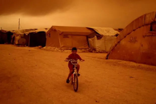 A boy rides a bike during a sandstorm in Syria's Idlib on June 2. (AP)