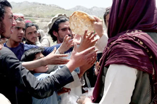 أفغان يتلقون خبزاً مساعدةً في منطقة تضررت بالزلزال أمس (رويترز)