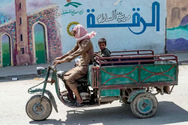 رجل وابنه يستقلان عربة في مدينة الرقة شمال سوريا في 19 يونيو الجاري (أ.ف.ب)